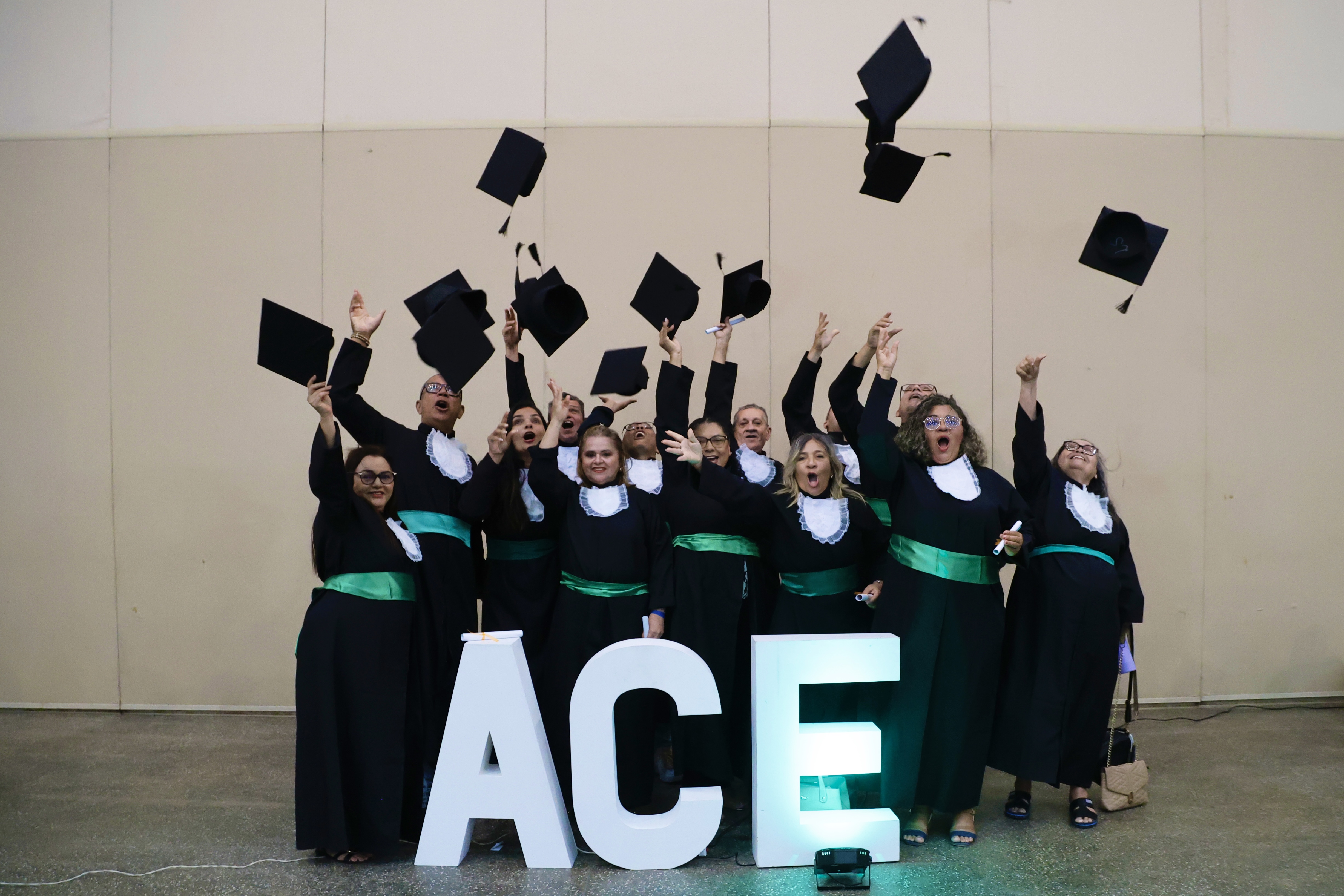 grupo de pessoas de beca posa para a foto jogando os chapéus para cima